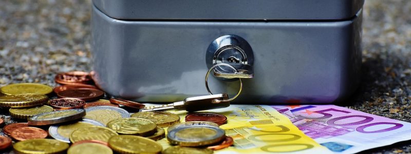 Notgroschen aufbauen – Geldkassette mit verteiltem Bargeld als Symbol für Rücklagen