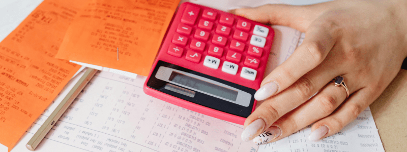 Steuererklärung machen – Hand mit pinkem Taschenrechner auf Belegen