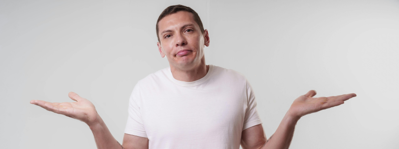 Mann hebt ratlos die Schultern – Symbol für vom Denken ins Handeln